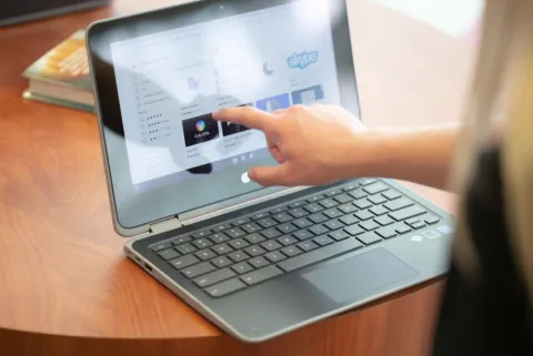 Hand pointing to a touchscreen laptop