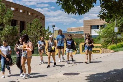 students walking in front of the large UCCS letters on the main sidewalk