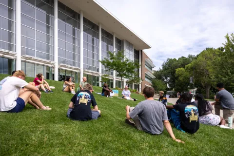students sitting in a circle in front of Dwire hall