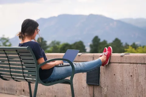 student sitting on her computer in front of the mountains