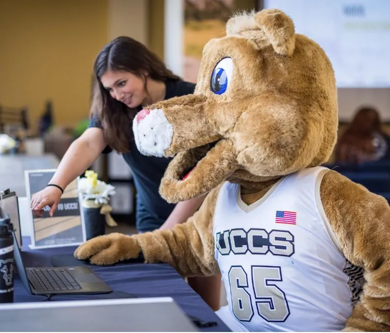 Student guiding the mascot Mountain Lion on the computer