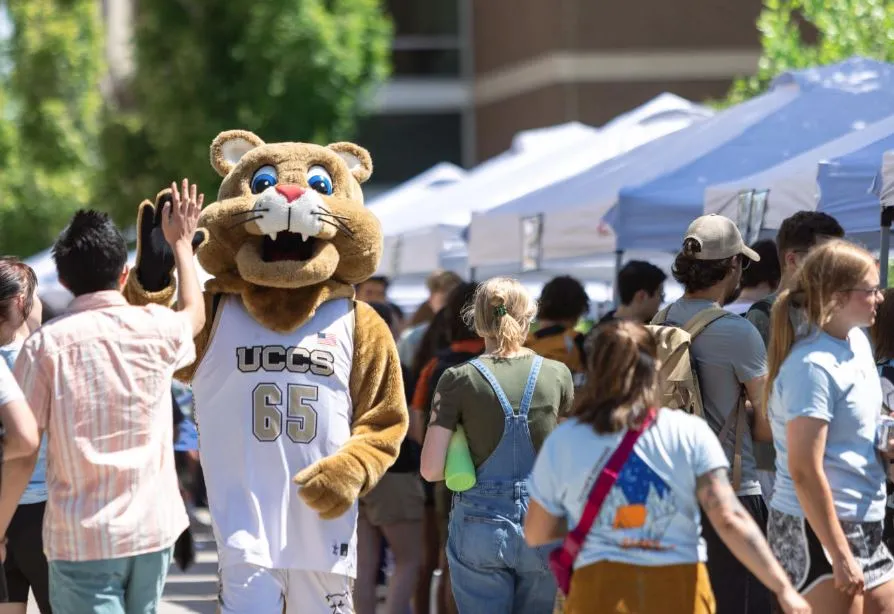 Clyde the Mountain Lion giving a high five at an orientation event. 